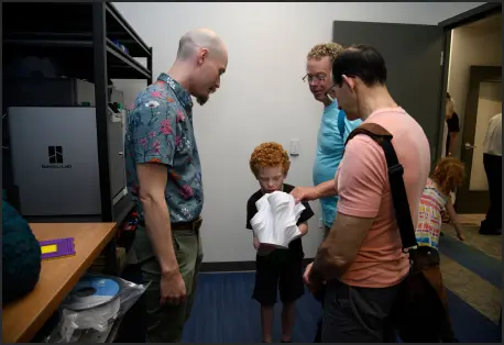Three adults showing a young boy a 3d printed object in ArtsCenters MakerSpace
